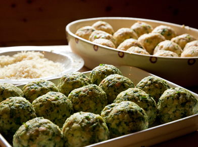 Frisch zubereitete Spinat- und Käseknödel auf einem Tablett, bereit zum Kochen.