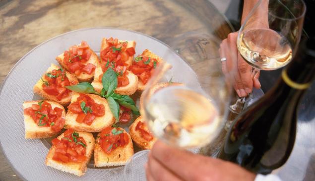 Ein Teller mit Bruschette und zwei Gläser mit Weißwein