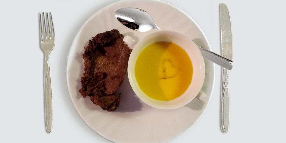 Piatto con zuppa di zucca in tazza e arrosto; un cuore decorativo appare sulla superficie della zuppa.