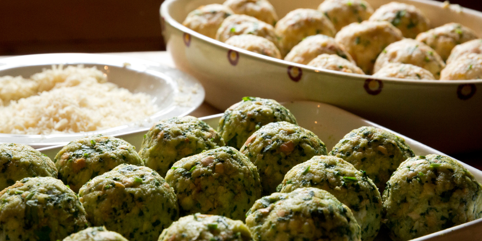 Canederli freschi agli spinaci e formaggio su un vassoio, pronti per la cottura.